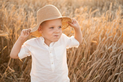 Portrait of young woman wearing hat standing on field