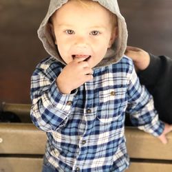 Portrait of cute boy wearing hood standing on bench