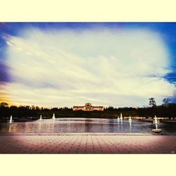 Swimming pool by lake against sky during sunset