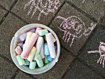 High angle view of chalks in container on pavement