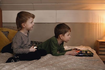 Kids playing video games at home on the bed at night. boys using game console and having fun in the