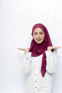 Portrait of young woman standing against white background