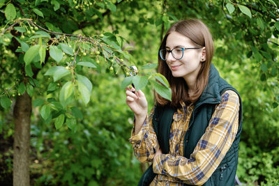 Young woman wearing hat standing against plants