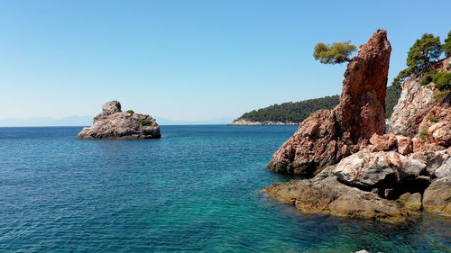 Scenic view of rock formation in sea against clear sky