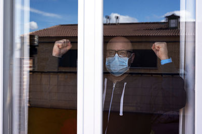 Portrait of man standing by window