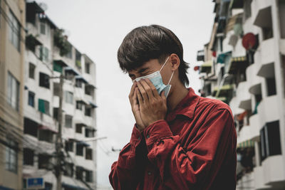 Portrait of young man standing against built structure