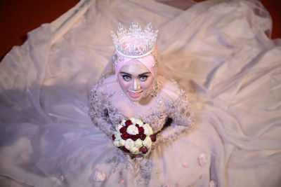 High angle portrait of woman wearing mask on bed
