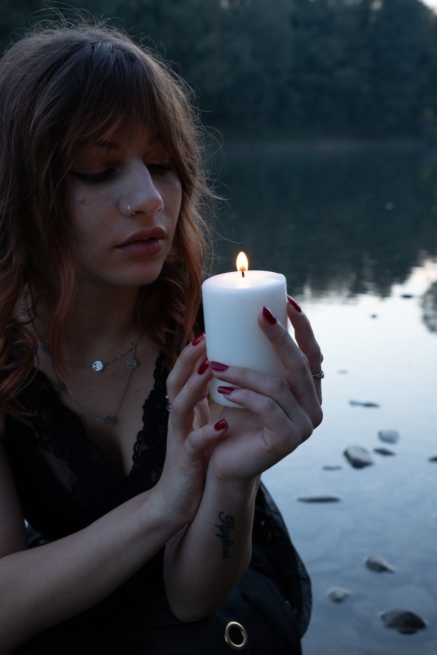 CLOSE-UP OF WOMAN WITH HANDS HOLDING BURNING