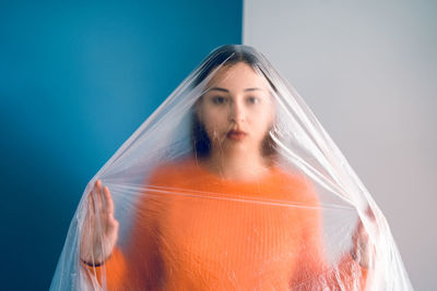 Portrait of teenage girl wrapped in plastic against wall