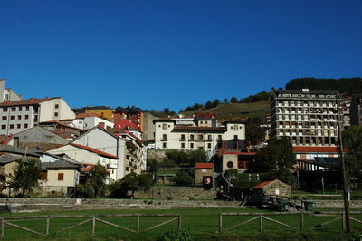 Buildings in town against clear blue sky