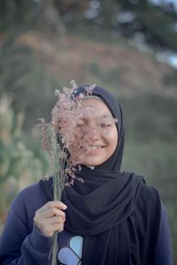 Portrait of woman holding plant against blurred background