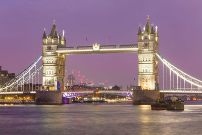 Illuminated bridge over river at night