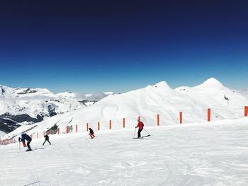 People skiing on snow covered mountains against sky