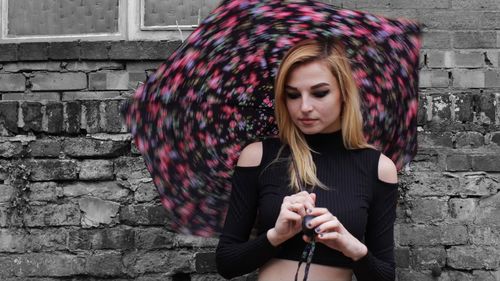 Young woman standing by wall