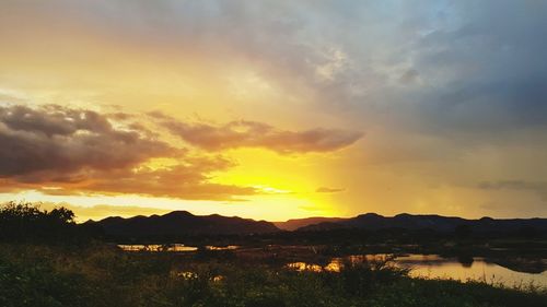 Scenic view of dramatic sky over silhouette landscape during sunset