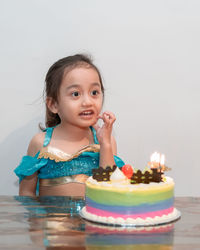 Portrait of cute girl looking away against wall