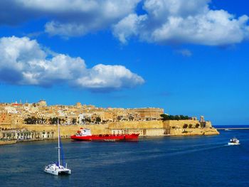 Sailboats sailing in sea against sky in city