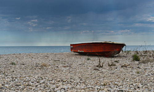 Boat moored on beach against sky