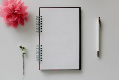 Directly above shot of book with pencil on note pad on table