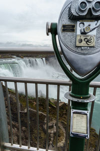 Close-up of coin-operated binoculars by sea against sky