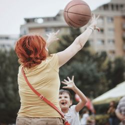Rear view of woman playing basketball in city
