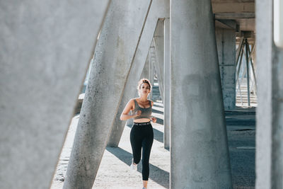 Female athlete running between column