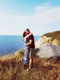 Woman with arms raised against sea against sky