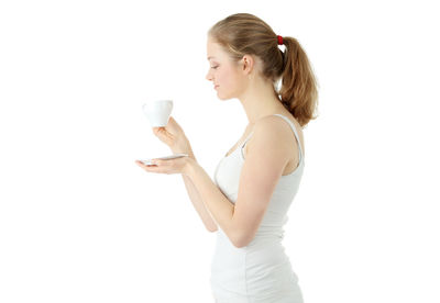 Side view of young woman drinking coffee against white background