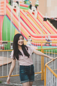 Portrait of smiling young woman standing at amusement park