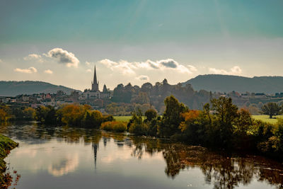 Scenic view of lake by trees and buildings against sky