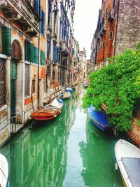 Boats moored in canal amidst city