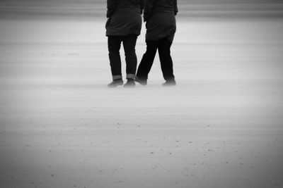 Low section of man walking on beach