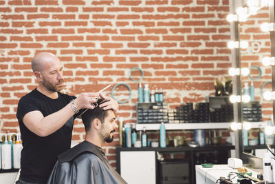 Barber cutting hair of customer in salon