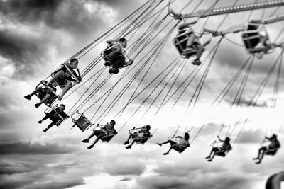 Low angle view of boys sitting on chain swing ride at amusement park