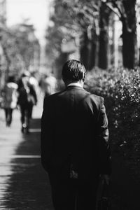 Rear view of man walking on footpath in city