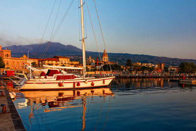 Sailboats moored at harbor against sky in city