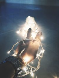 Close-up of illuminated lighting equipment against sky