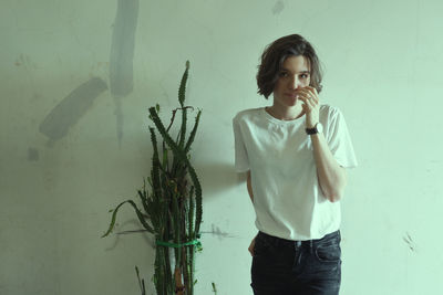 Portrait of young woman standing against wall