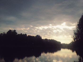 Silhouette trees by lake against sky during sunset