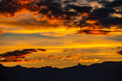 Scenic view of silhouette mountains against orange sky