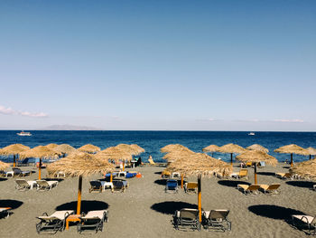Chairs and parasols on beach against clear sky