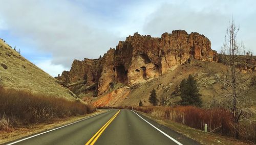 Empty road leading towards rock formation