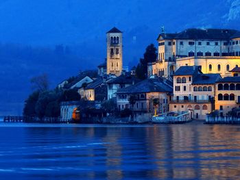 Buildings by lake during dusk