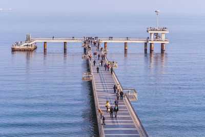 People on bridge over sea against clear sky