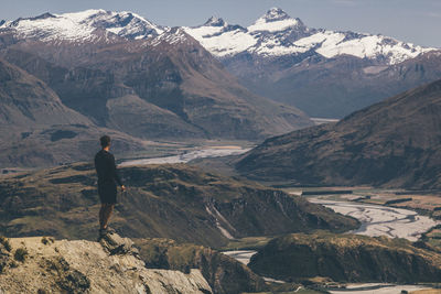 Rear view of man standing on mountain against sky