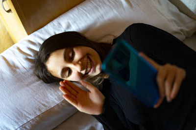 Woman in bed talking on video call.