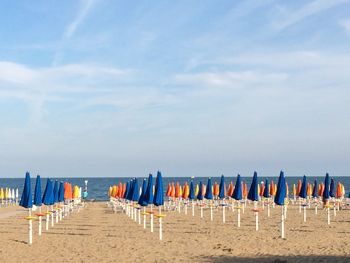 Panoramic view of parasols on beach against sky