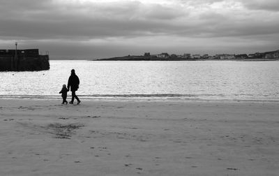 Man walking on beach against sky