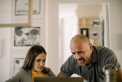 Father and daughter using laptop in kitchen at home