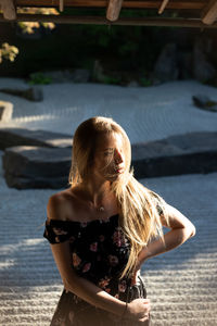 Young woman looking away while standing outdoors